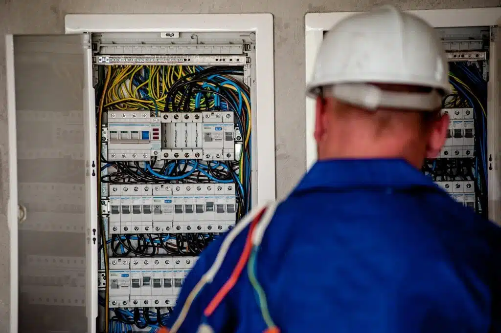 Električar sa zaštitnom kacigom ispred otvorenog električnog razdjelnika