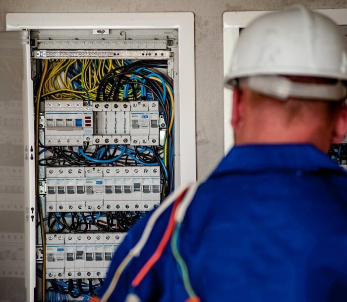 Električar sa zaštitnom kacigom ispred otvorenog električnog razdjelnika