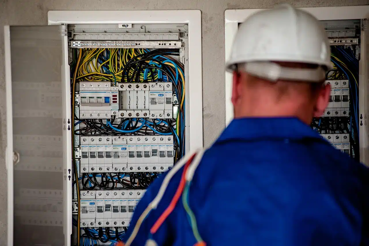 Električar sa zaštitnom kacigom ispred otvorenog električnog razdjelnika